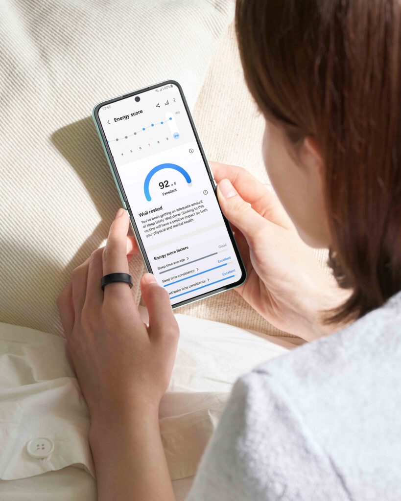 Frau prüft Schlaf- und Energiewerte in der Samsung-Health-App, dazu ein Galaxy Ring am Finger